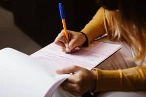 A woman signing a document, showing the necessity of flood insurance