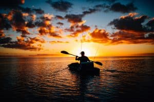 A man kayaking at sunset