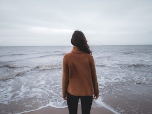 Woman facing the ocean in cold weather