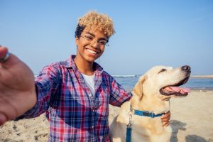 Woman taking a selfie with her dog on the beach